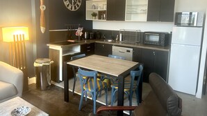 A compact kitchen with a dining area, featuring a microwave, toaster, and a sink. - Maison de Ville Avec Jardin Proche du Pont Canal (Briare)