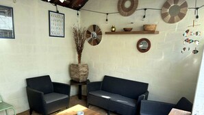 A cozy room with a dark-colored sofa, two armchairs, and a wooden coffee table. There are decorative items on the walls, including a clock and a framed picture. - Maison de Ville Avec Jardin Proche du Pont Canal (Briare)