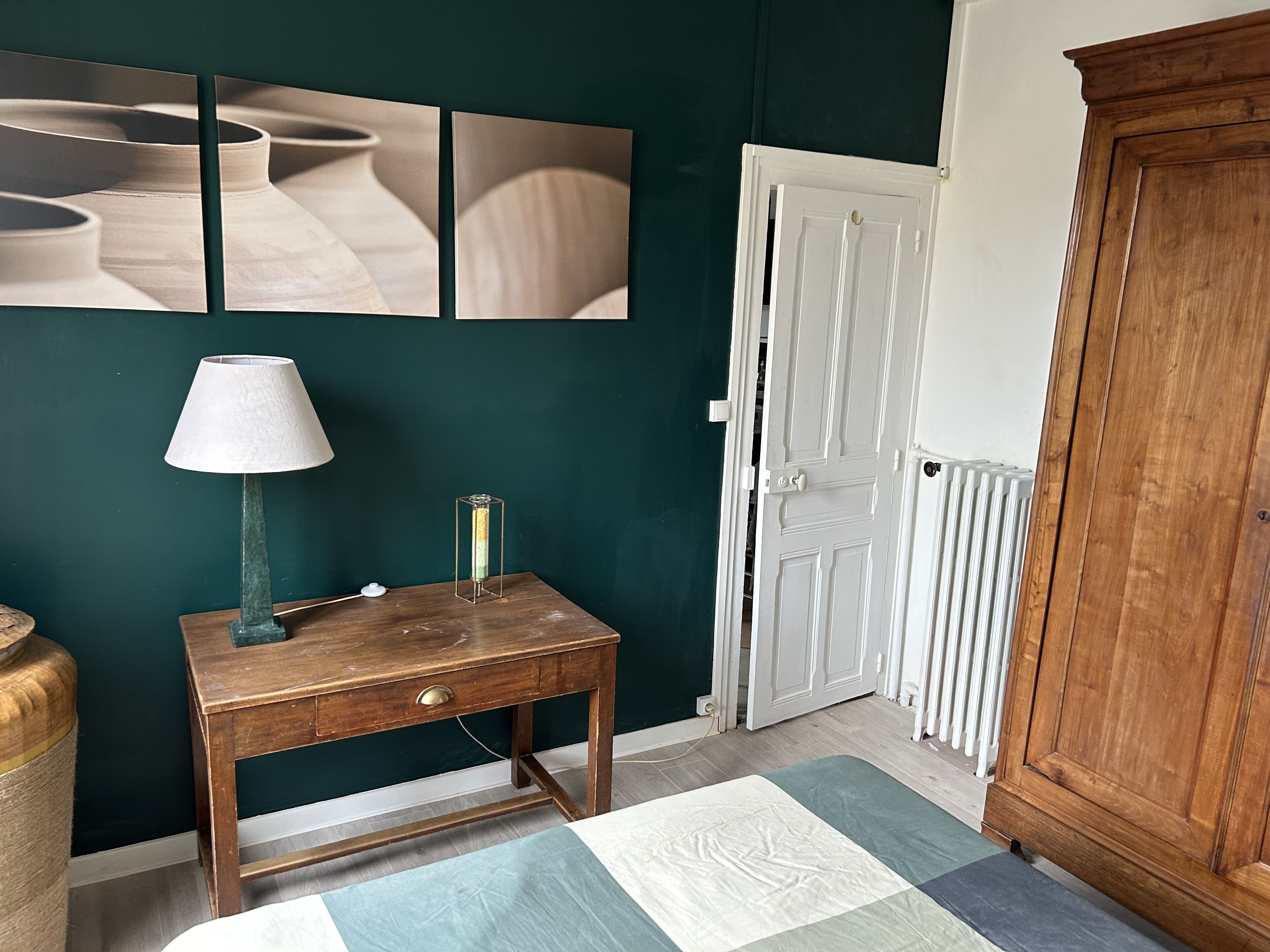 Una habitación con escritorio de madera, lámpara, radiador y puerta.