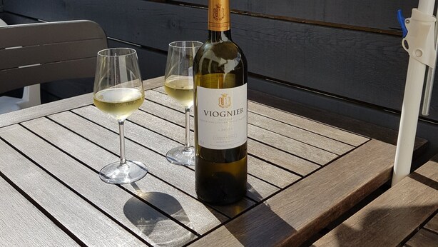 A bottle of Viognier wine and two glasses on a wooden table outdoors. - House, Central Village location, near cafe/boulangerie, 300m from coast. (Saint Armel)