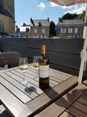 A bottle of Viognier wine and two glasses on a wooden table outdoors.