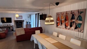A modern living room with a fireplace, red sofa, dining table, and artwork on the wall. - House, Central Village location, near cafe/boulangerie, 300m from coast. (Saint Armel)
