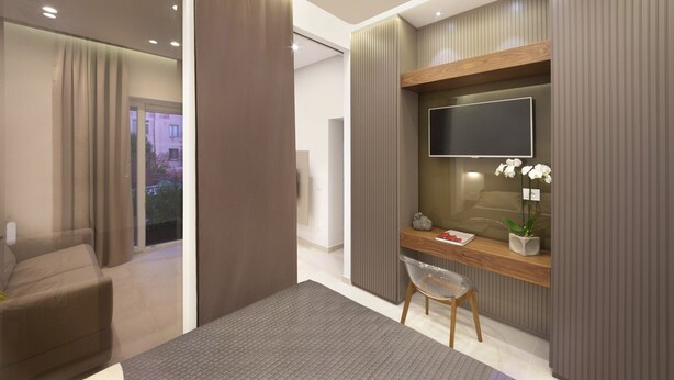 Une chambre d’hôtel moderne équipée d’un bureau, d’une chaise et d’un téléviseur fixé au mur.