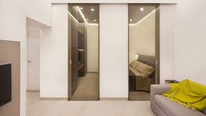 Un salon moderne avec un canapé, un téléviseur et une porte coulissante donnant sur une chambre à coucher.