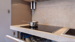 Une cuisine moderne équipée d’une plaque de cuisson à induction intégrée, d’un lave-vaisselle et d’une casserole en acier inoxydable posée sur le plan de travail.