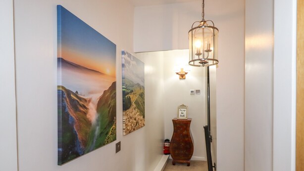 Un escalier agrémenté d’un luminaire fixé au mur et de deux tableaux représentant des paysages.