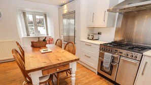 Une cuisine moderne avec des meubles blancs, une table à manger en bois et une cuisinière en acier inoxydable.
