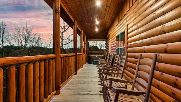 A wooden log cabin with a covered porch and several wooden benches. - New! Pet Friendly, Private Pool, Media Room, Golf! (Sevierville)