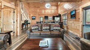 A cozy cabin interior with a wooden interior, a dining area, and a sofa with patterned cushions. - New! Pet Friendly, Private Pool, Media Room, Golf! (Sevierville)