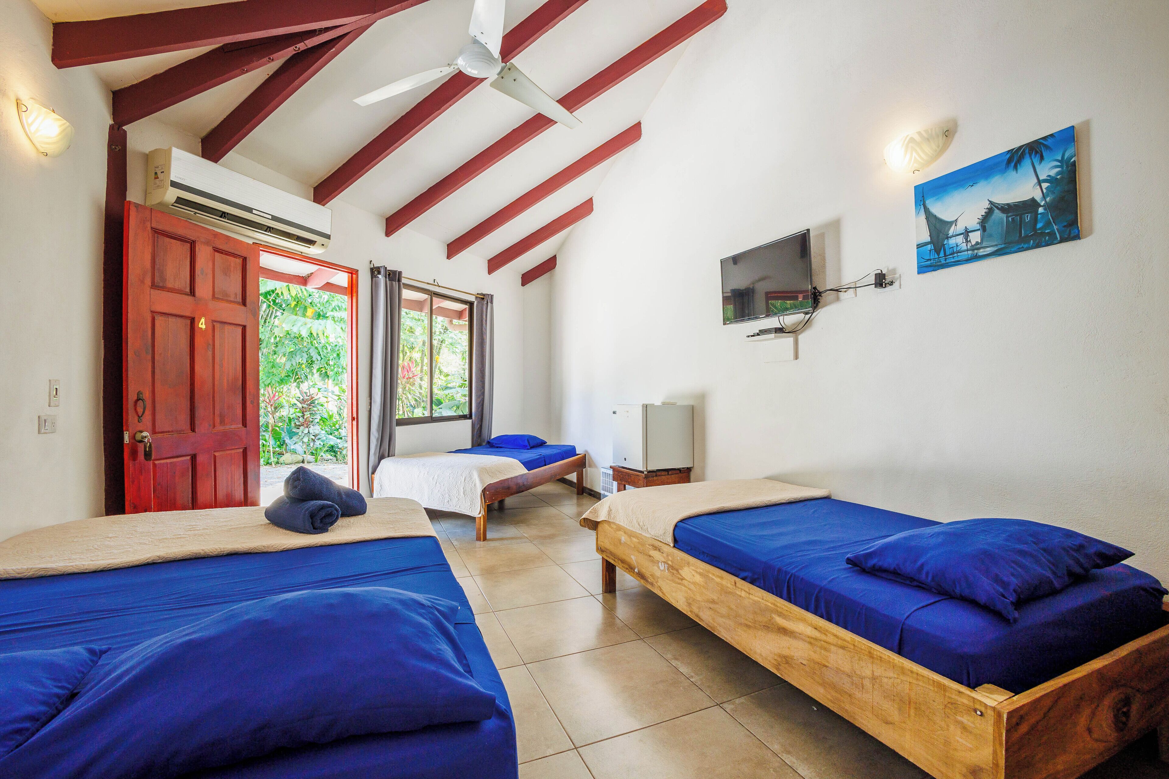 A room with two wooden beds, a TV, and a painting on the wall.