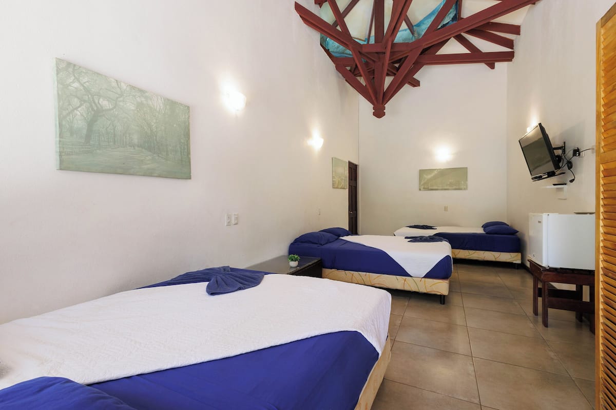 A hotel room with two beds, a TV, and a painting on the wall.