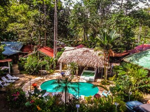 Ett tropiskt semesterparadis med en pool, solstolar och byggnader med halmtak.