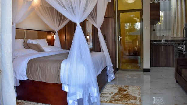 Une chambre à coucher avec un lit à baldaquin, une salle de bain avec une porte en verre et un coin cuisine.