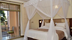 Une chambre à coucher avec un lit à baldaquin, un balcon avec un fauteuil et une vue sur l’extérieur.