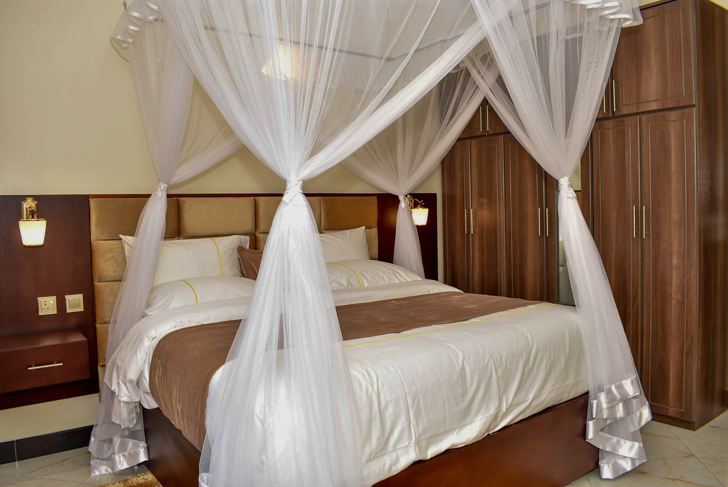 A hotel room with a four-poster bed, wooden headboard, and a nightstand with a lamp.