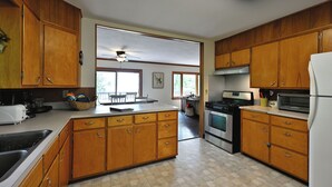 A kitchen with wooden cabinets, a central island, a refrigerator, and a stove. - Sandy Shore Lodge- beautiful, private sand beach awaits! (Shell Lake)