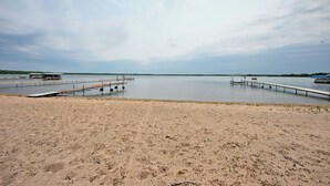 A sandy beach with a wooden pier extending into calm water. - Sandy Shore Lodge- beautiful, private sand beach awaits! (Shell Lake)
