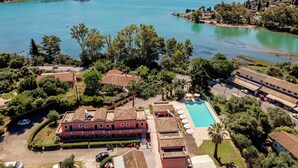An aerial view of a coastal resort with a swimming pool, multiple buildings, and a large body of water. - Ionian Arches Corfu (Corfu)