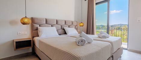 A bedroom with two beds, a nightstand, a hanging lamp, and a balcony with a view.