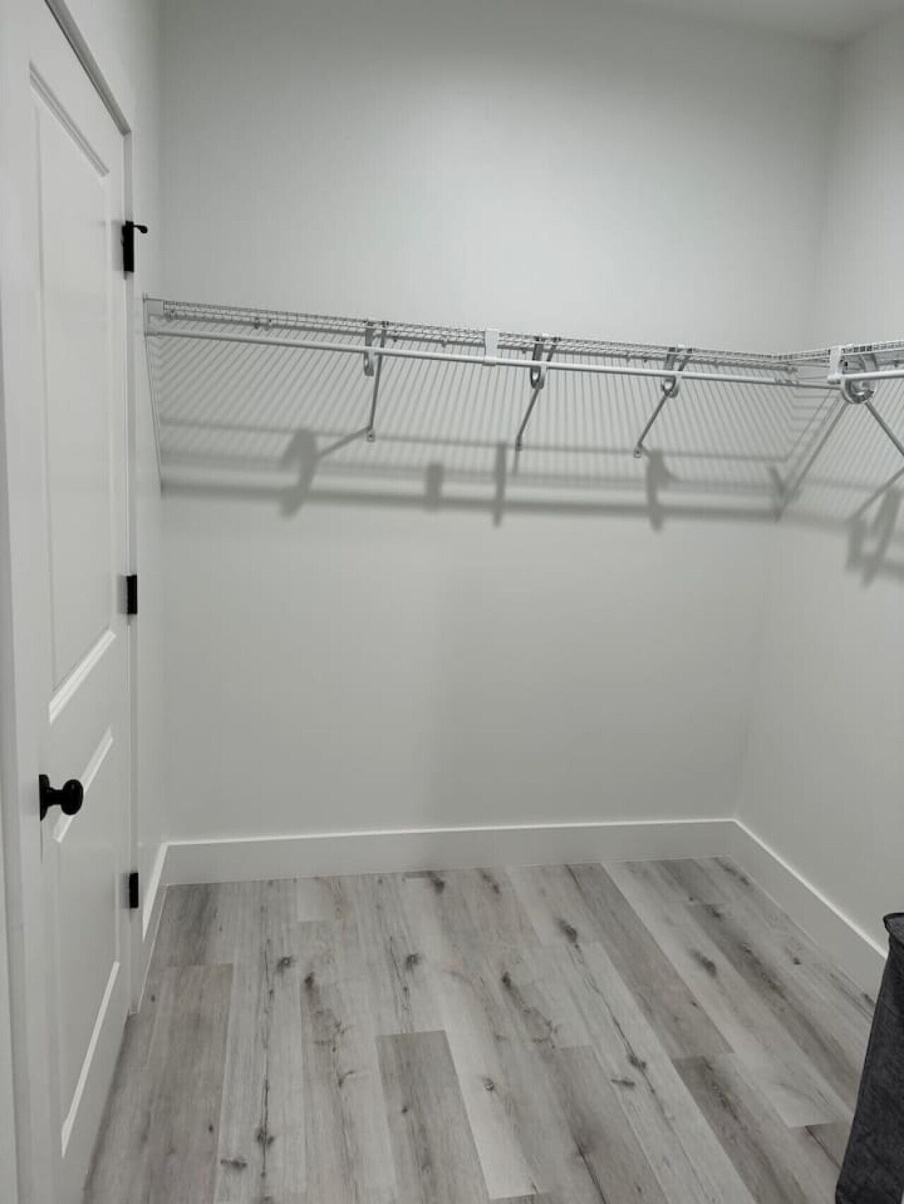 Una habitación con piso de madera, paredes blancas y un tendedero de metal.