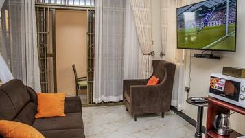 A living room with a sofa, armchair, and a television mounted on the wall.
