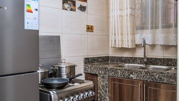 A kitchen with a stove, pots, a sink, and wooden cabinets.