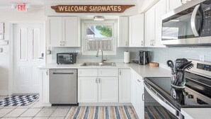A modern kitchen with white cabinetry, a microwave, a dishwasher, and a coffee maker.