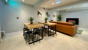 Una sala de estar moderna con un sofá, una mesa de comedor con sillas y un televisor de pantalla plana montado en la pared.