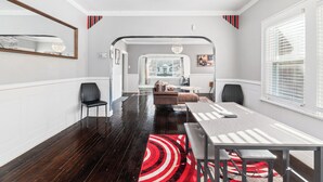 A modern dining area with a long table, chairs, and a red and white striped rug. - 15 mins to beach/Renew+Relax/Clean/ Nat’l Park!/Theater/Game Room/Pet Friendly (Gary)
