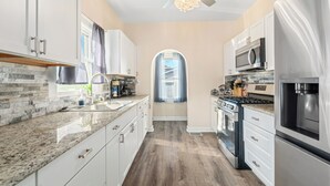 A modern kitchen with granite countertops, stainless steel appliances, and white cabinetry. - 15 mins to beach/Renew+Relax/Clean/ Nat’l Park!/Theater/Game Room/Pet Friendly (Gary)