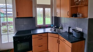 Una cocina con armarios de madera, encimera negra, ventana y salpicadero de azulejos.