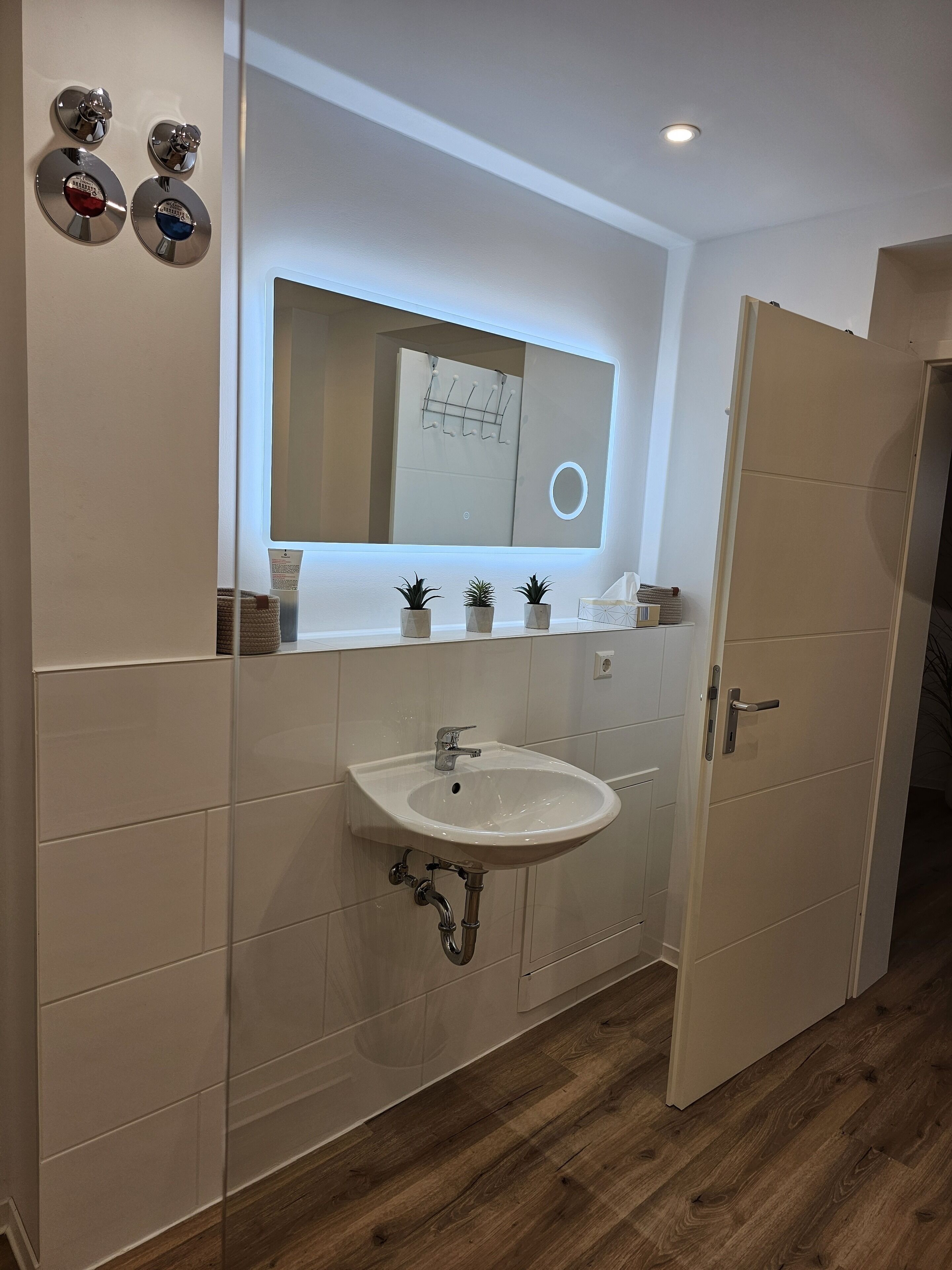 Ein Badezimmer mit einem weißen Waschbecken, einem Spiegel und einer Tür.