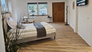 Een moderne slaapkamer met een bed, nachtkastje en een aan de muur bevestigde televisie.