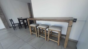 A room with a wooden bar stool set and a dining table with chairs.