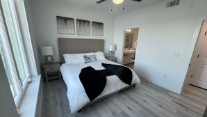 A bedroom with a bed, nightstands, a ceiling fan, and artwork on the wall. - Private Condo #208 with Riverside View and Private Pool (Gulfport)