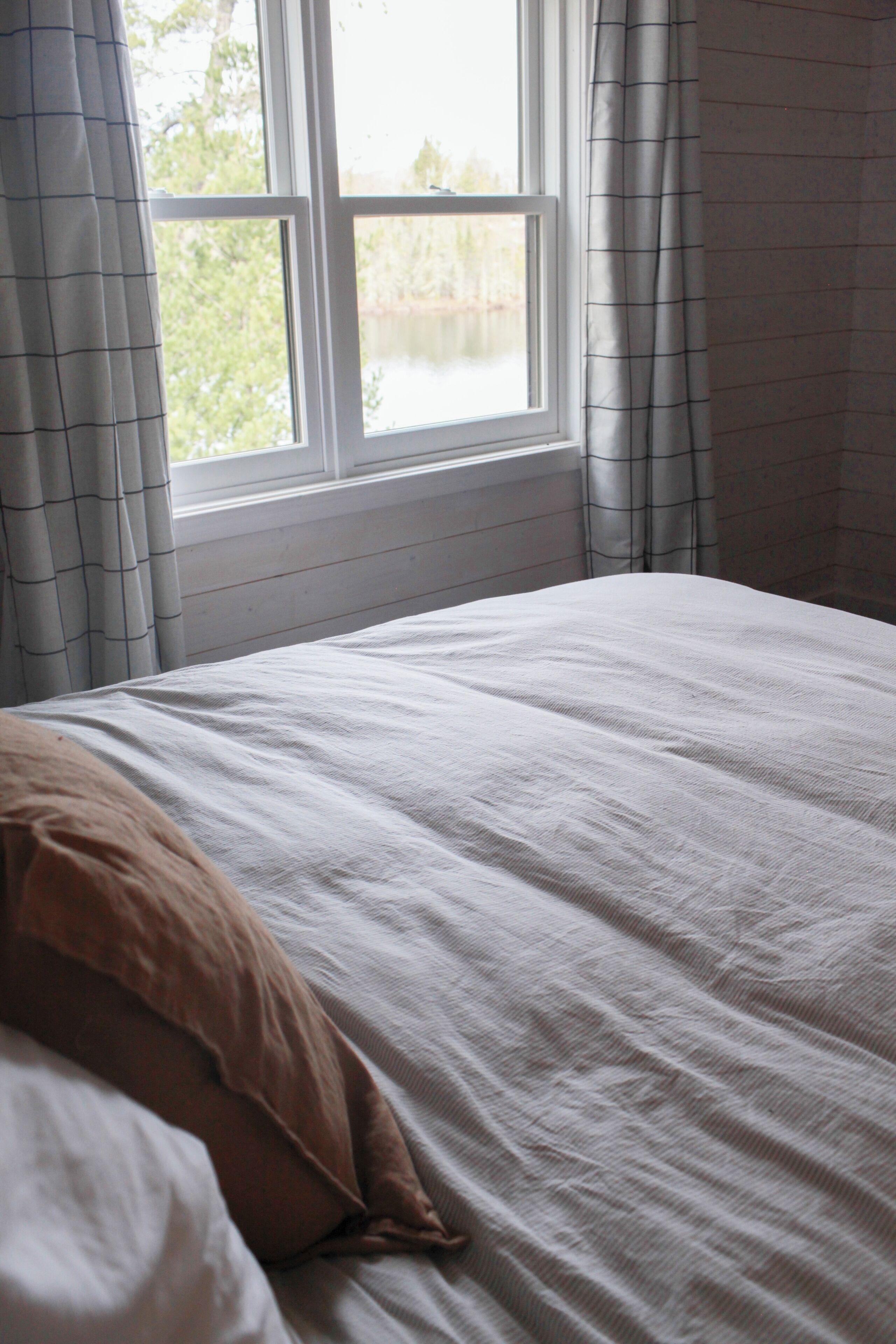 A bedroom with a bed, a window, and curtains.