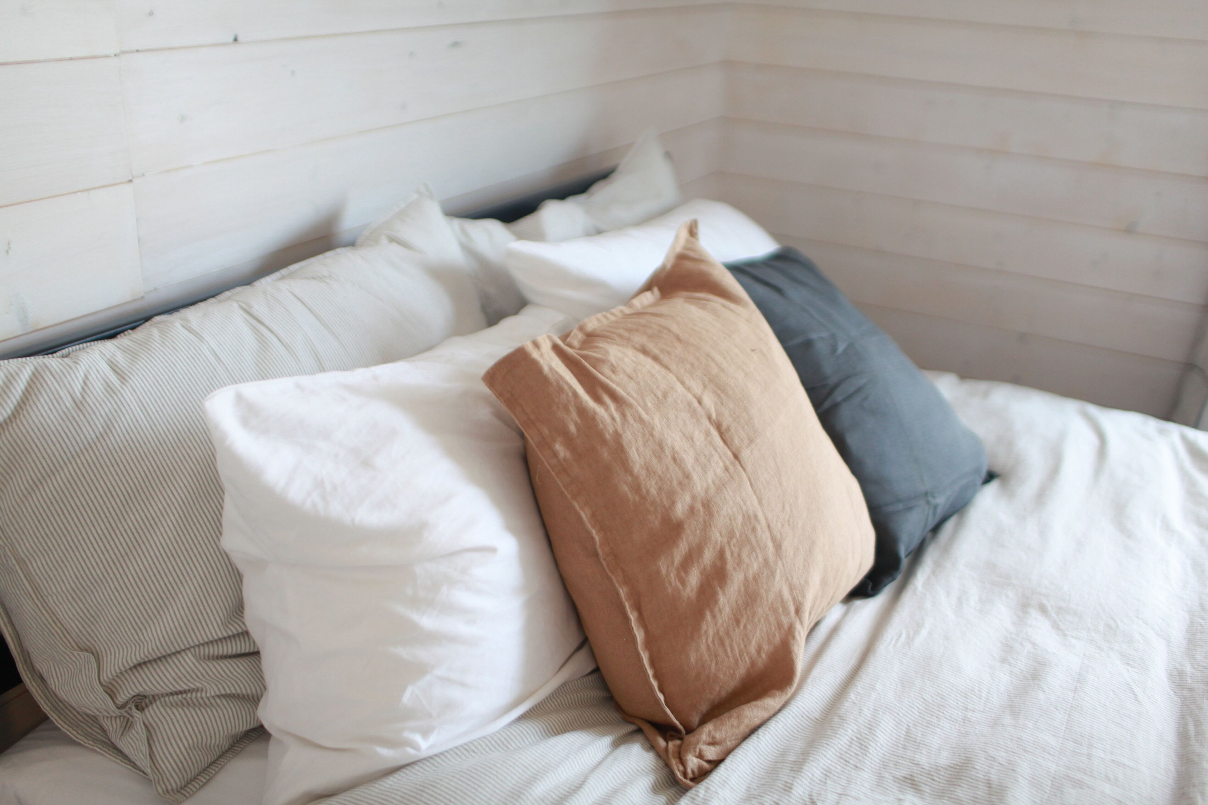 Una cama con muchas almohadas y una manta a rayas.