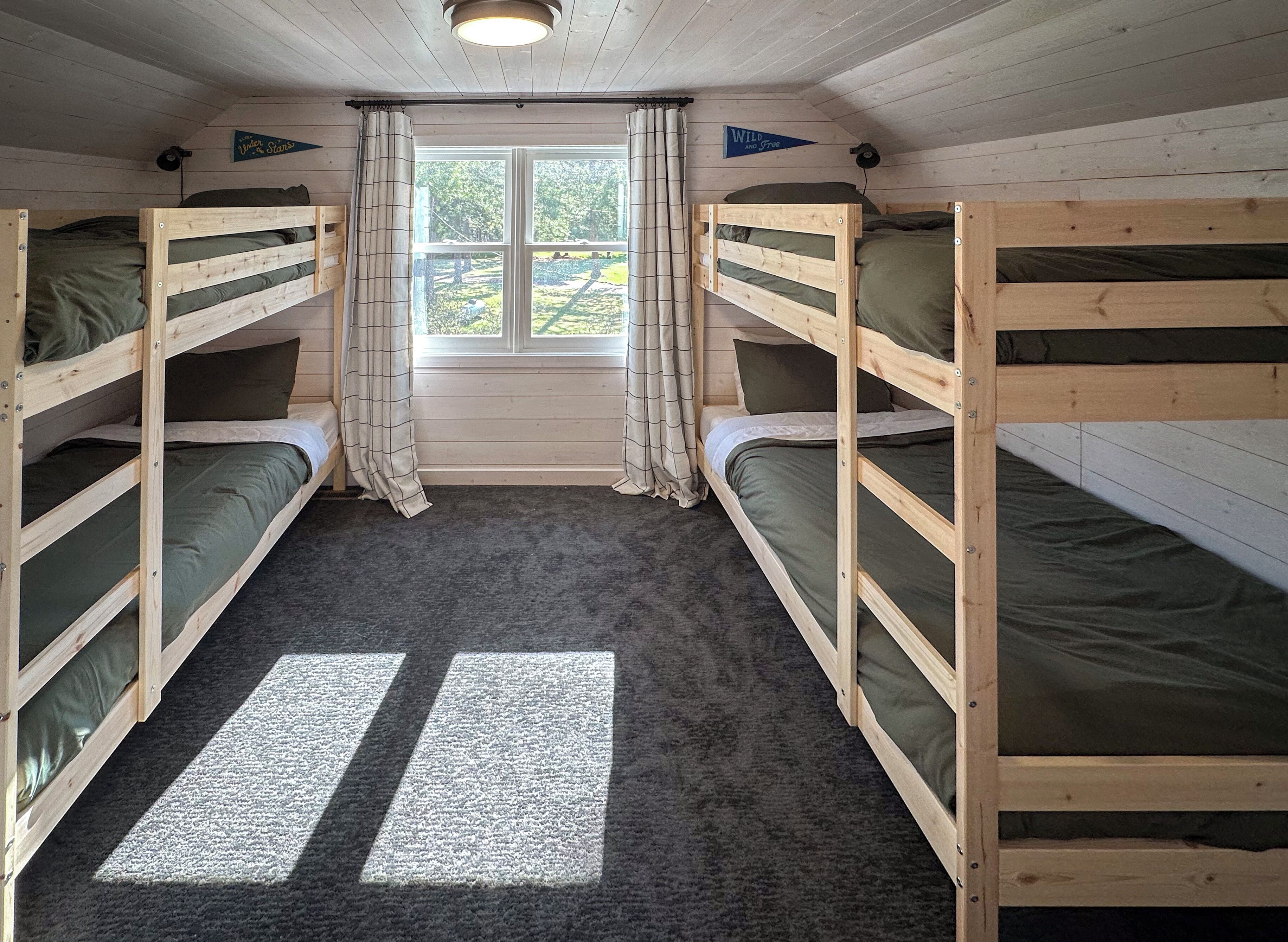 Ein Zimmer mit zwei Etagenbetten, einem Vorhangfenster und Teppichboden.