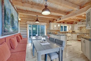 Cozy interior space with a dining area, comfortable sofa, and kitchen in the background.