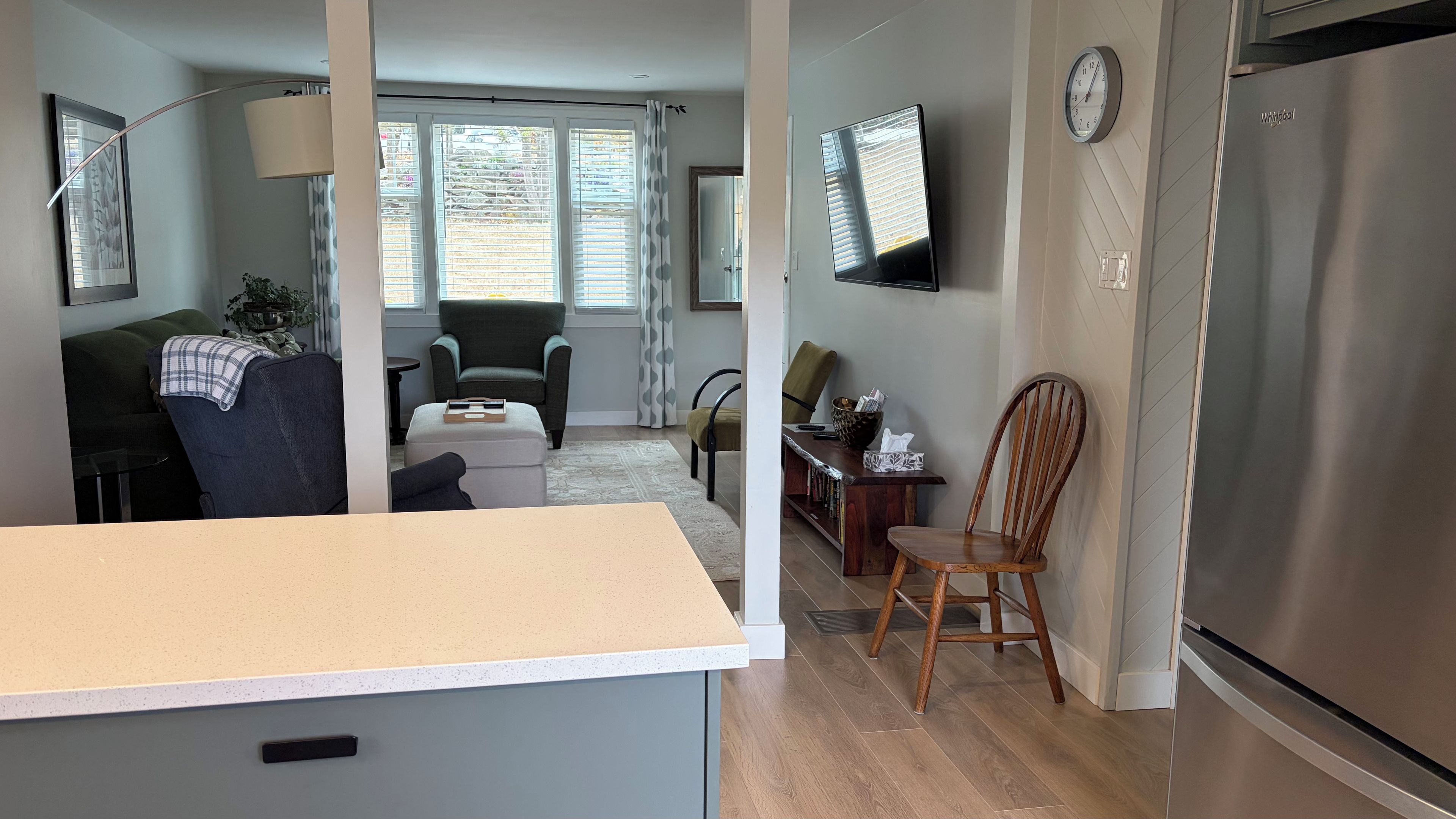 Une cuisine moderne dotée d’un réfrigérateur encastré, un coin repas avec une table et des chaises, et un salon avec un canapé et un téléviseur.