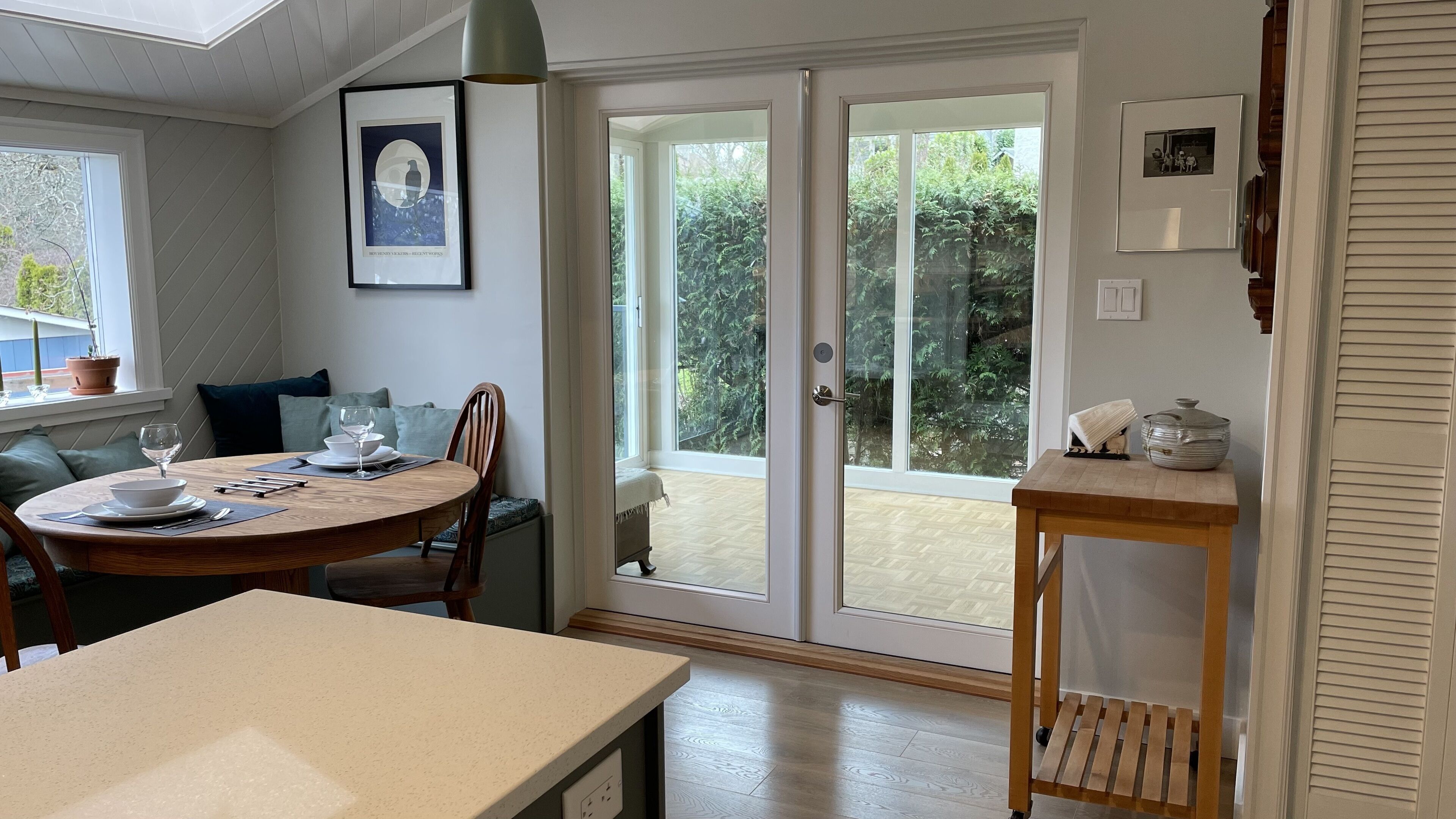A dining area with a round table, chairs, and a view through glass doors to an outdoor space.