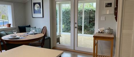 A dining area with a round table, chairs, and a view through glass doors to an outdoor space.