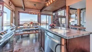 Une cuisine moderne dotée d’un grand îlot central, d’un plafond en bois et de grandes fenêtres offrant une vue sur l’extérieur.