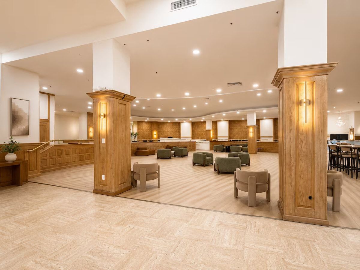 A spacious lobby with a reception desk, seating area, and wooden pillars.