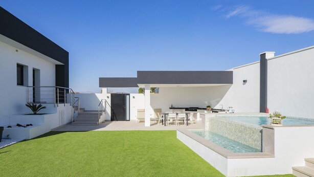 Uma casa moderna com piscina, varanda coberta e gramado bem cuidado.