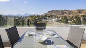 Uma mesa de jantar posta para quatro pessoas, com vista para uma paisagem montanhosa.