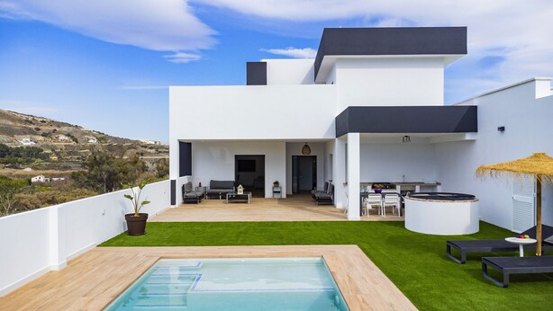 Ein modernes Haus mit Pool, Sitzgelegenheiten im Freien und Blick auf die Landschaft.