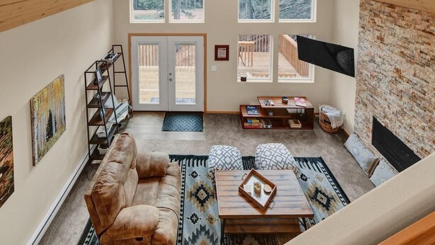 Una sala de estar estilo loft acogedora, con techo alto, ventanas amplias, chimenea y un rincón de descanso confortable.