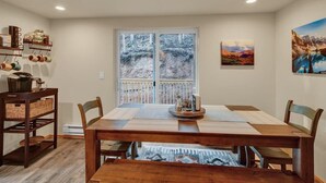 Un comedor con una mesa de madera, sillas y una ventana con vistas a árboles.