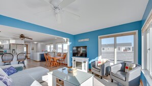 Uma sala de estar ampla com uma parede azul decorativa, lareira, televisão e área de jantar com mobiliário de madeira.